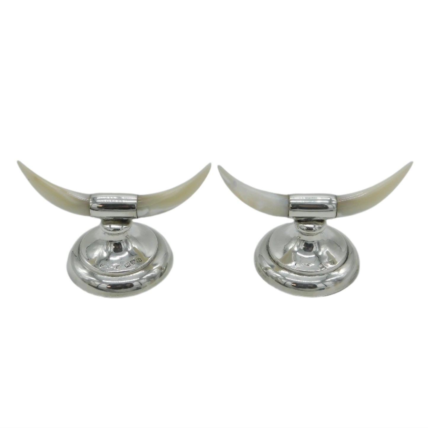 Two silver candle holders with long white horns on a light gray background
