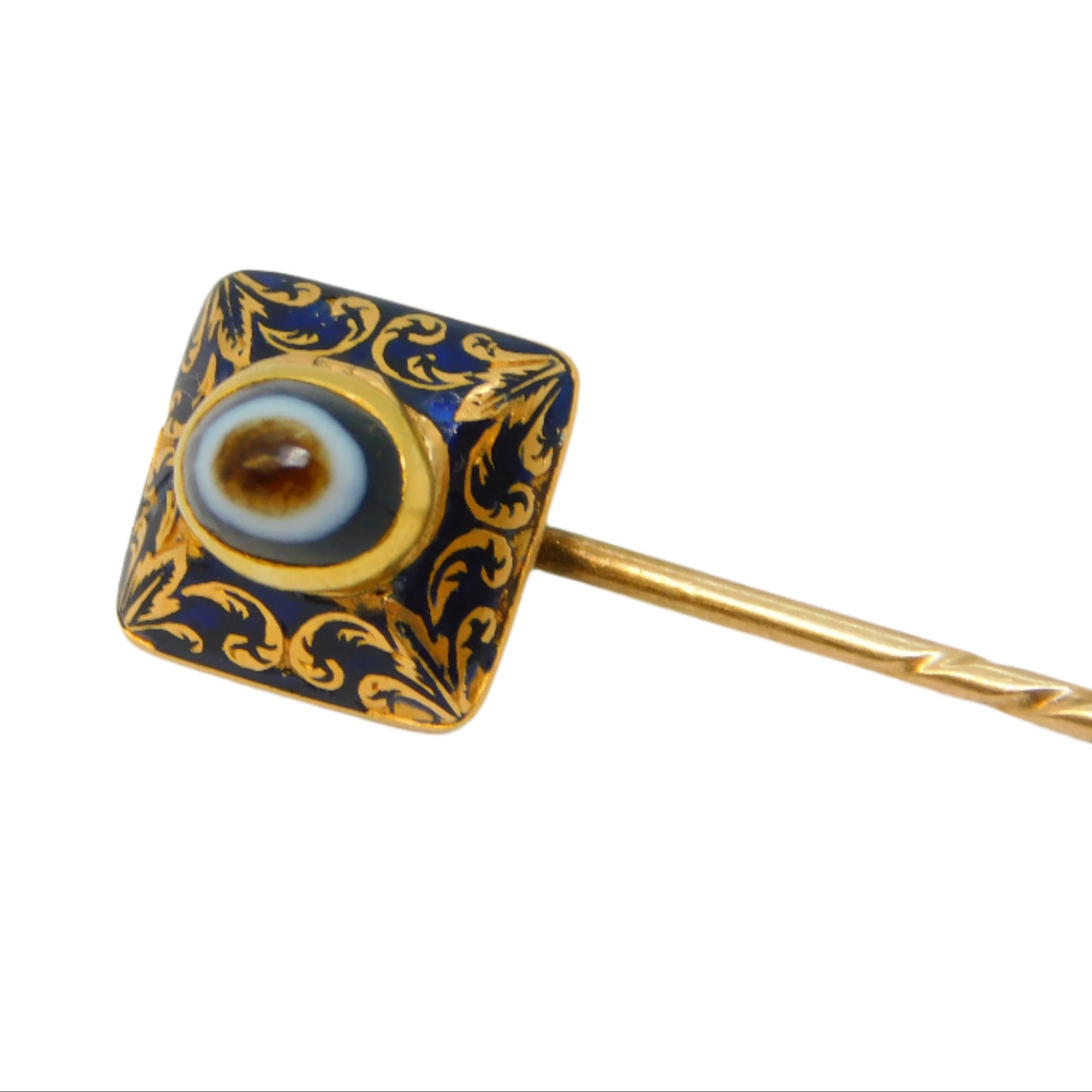 Decorative stickpin with blue enameled eye and gold accents on a white background