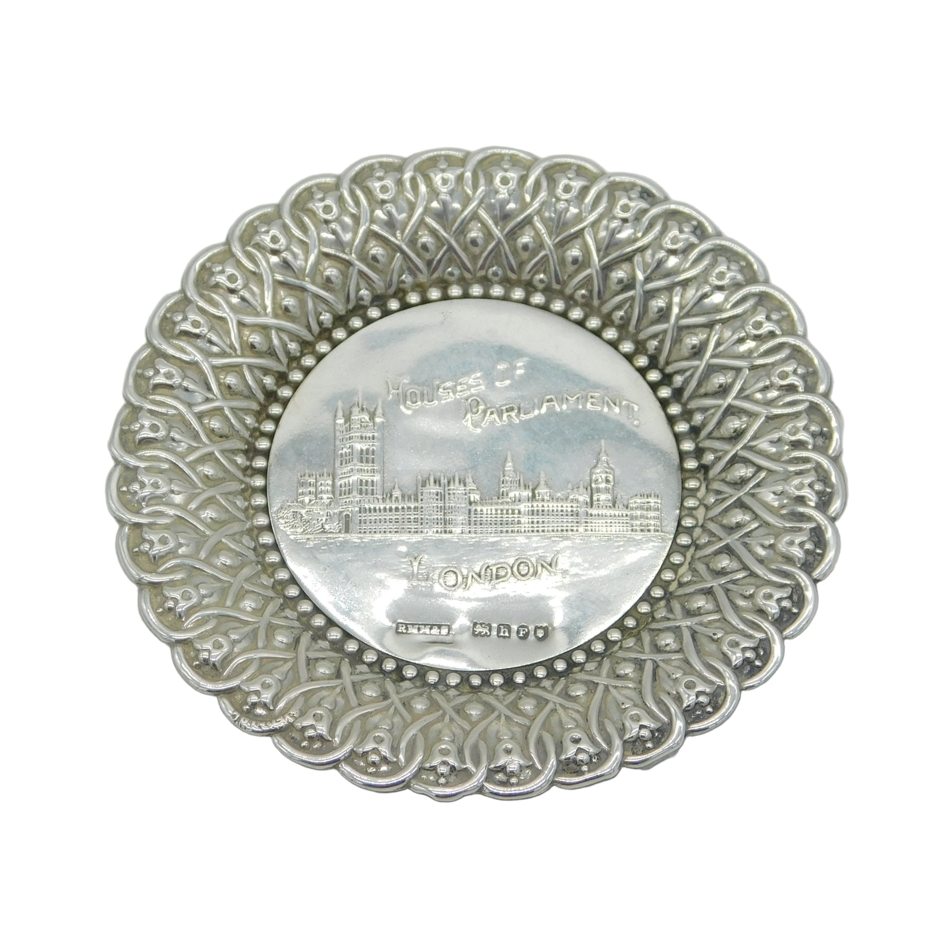 Decorative silver plate with intricate patterns and a central emblem on a white background
