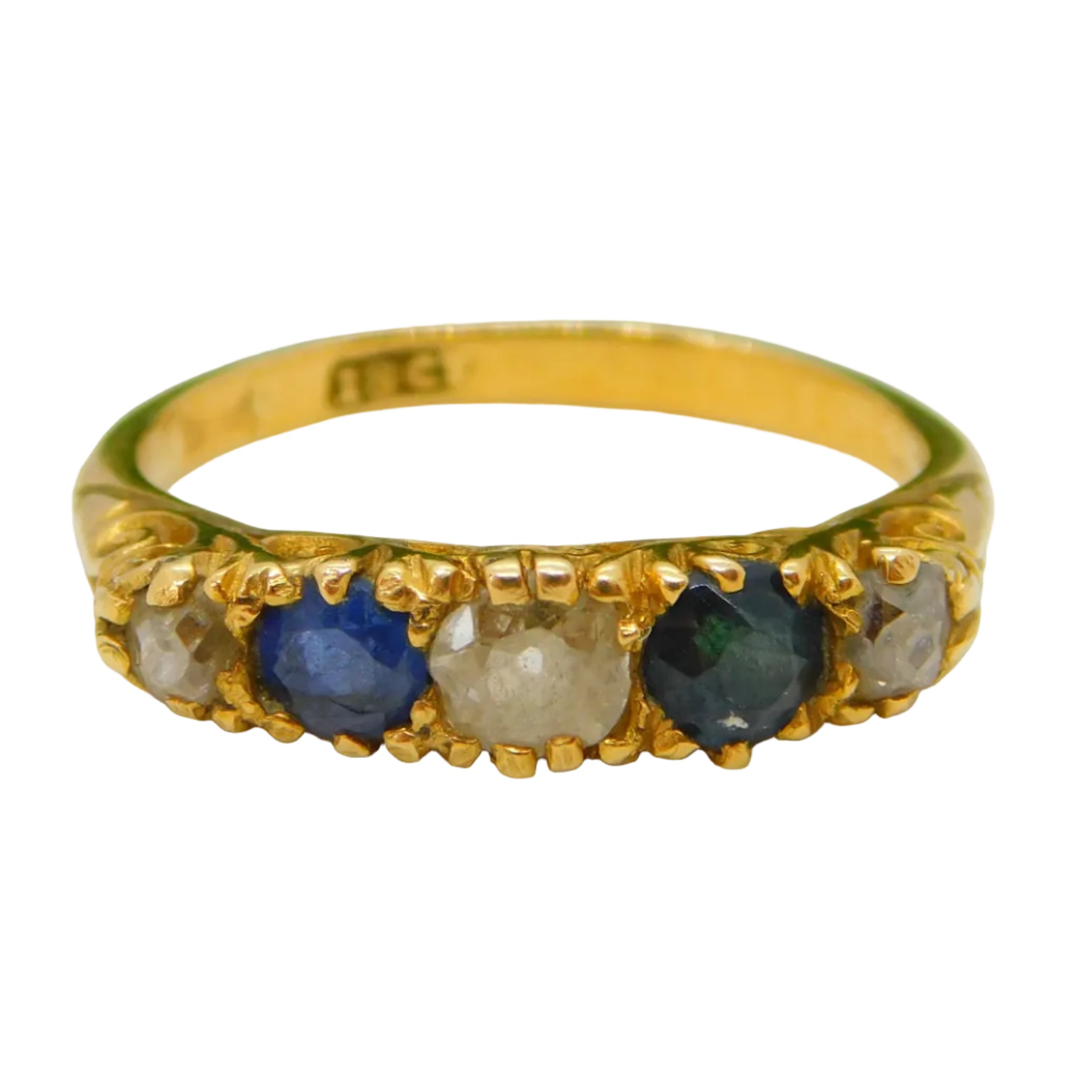 An 18ct yellow gold ring with a central diamond and sapphire stones, placed on a green velvet-like surface.