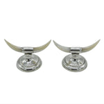 Two silver candle holders with long white horns on a light gray background