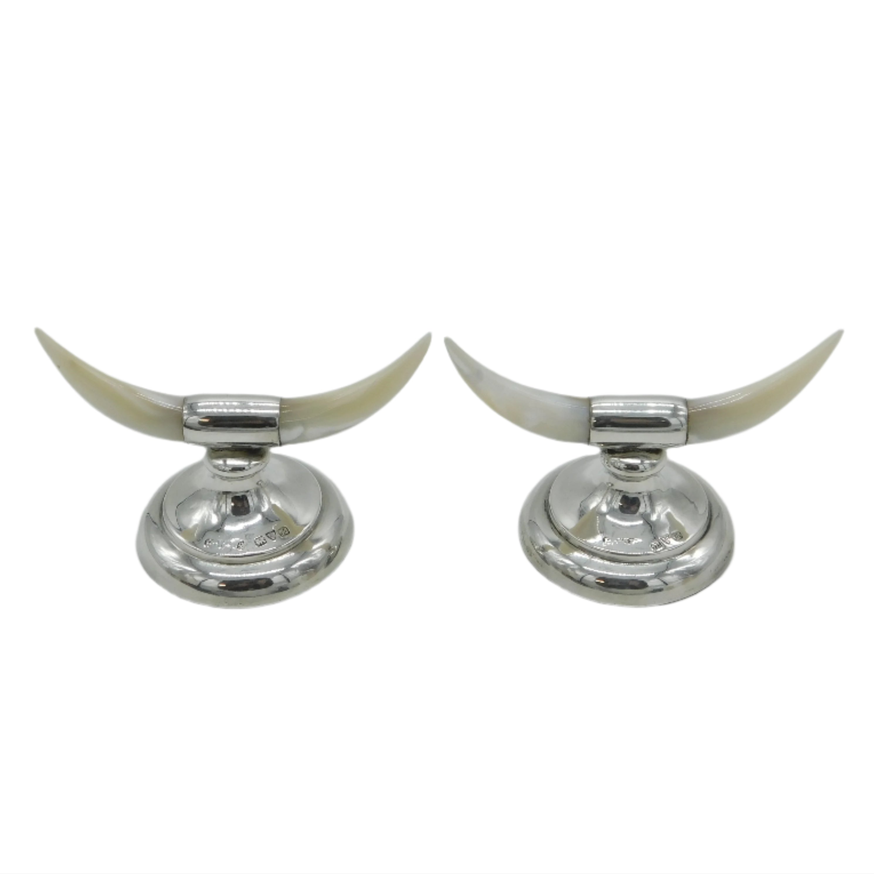 Two silver candle holders with long white horns on a light gray background