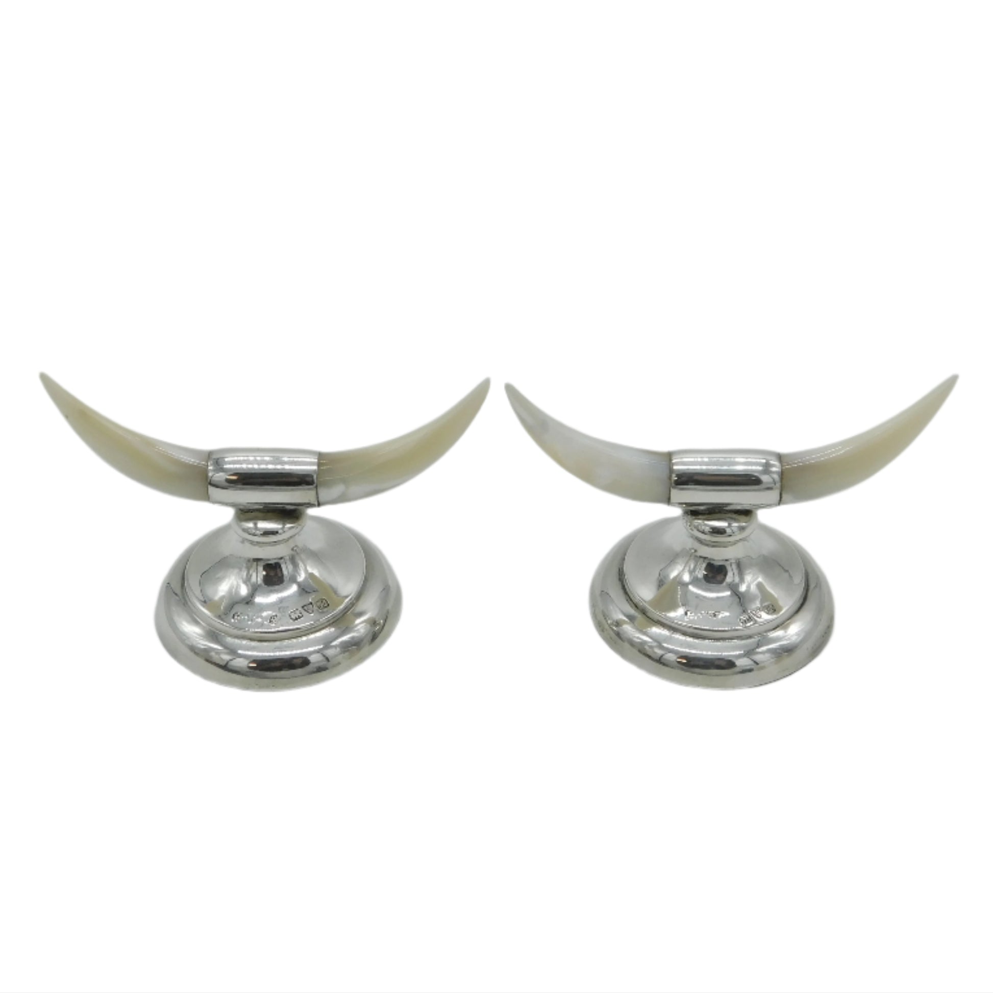 Two silver candle holders with long white horns on a light gray background