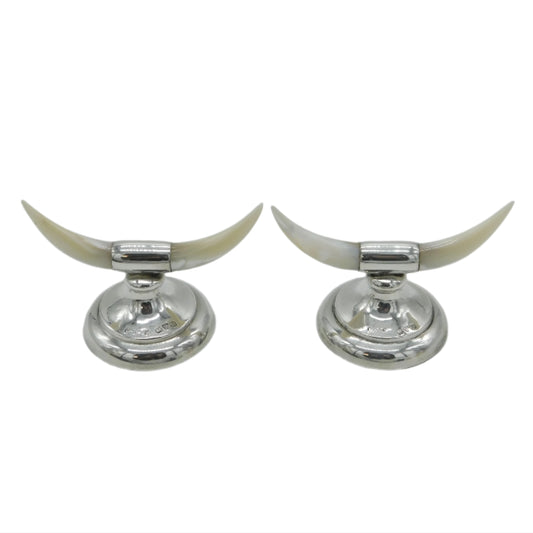 Two silver candle holders with long white horns on a light gray background