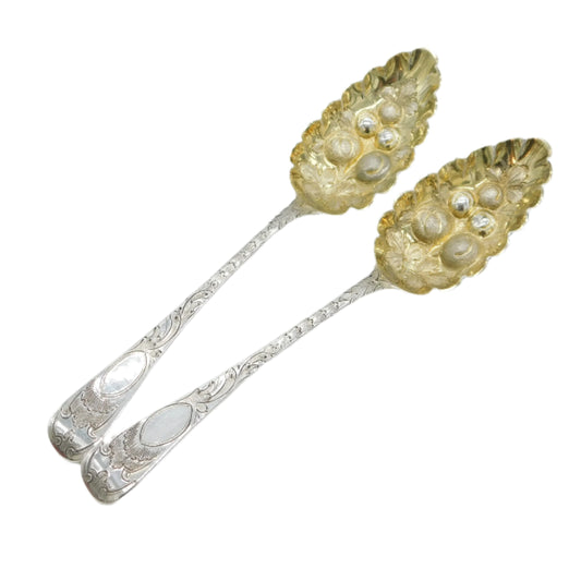Two silver spoons with decorative handles on a light gray background