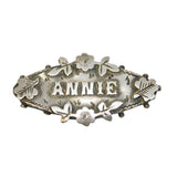 Silver brooch with 'ANNIE' engraved on a gray background