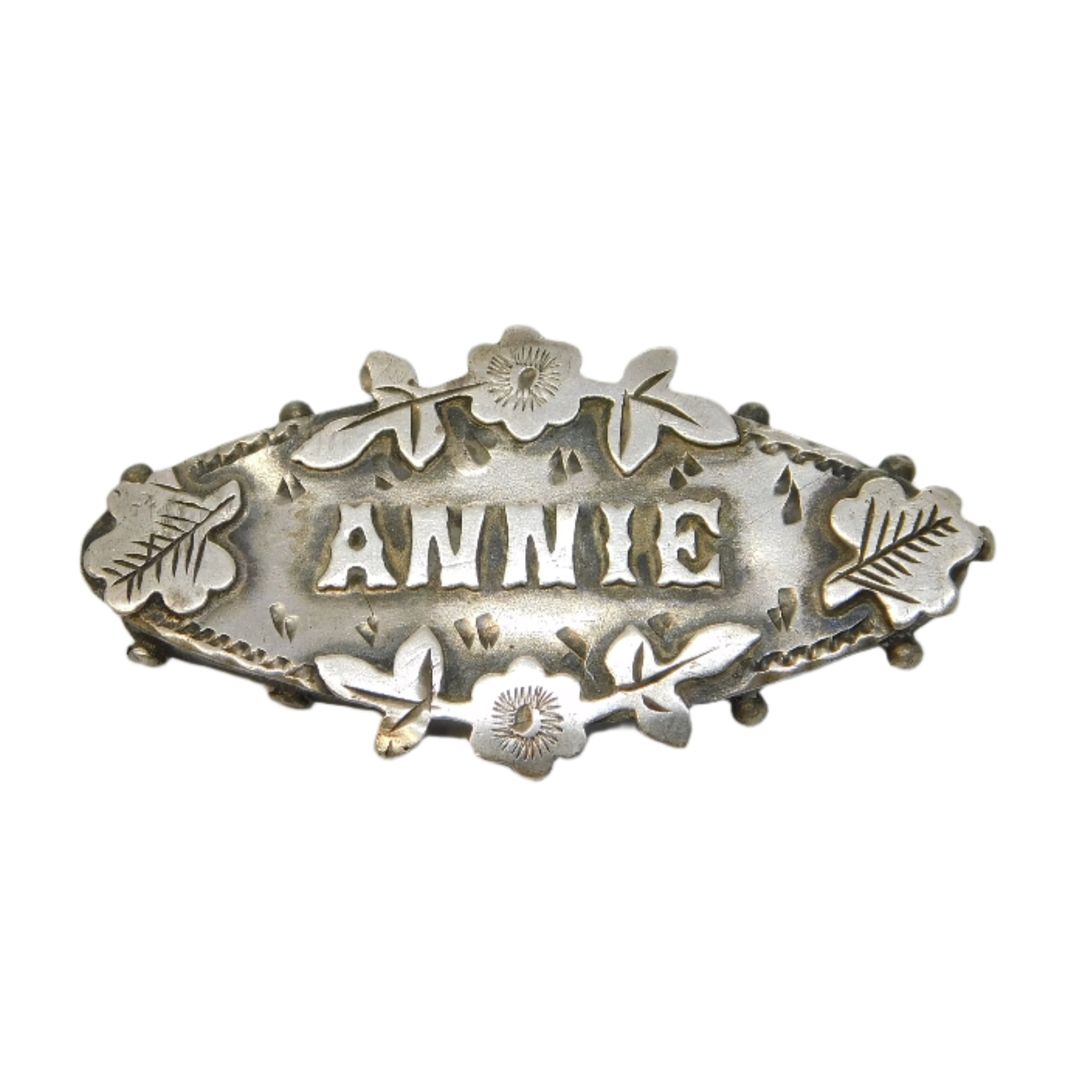 Silver brooch with 'ANNIE' engraved on a gray background