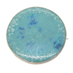 Round turquoise brooch with gold edge on a white background