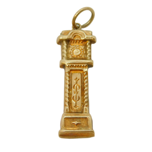 Gold pendant resembling a clock tower on a white background