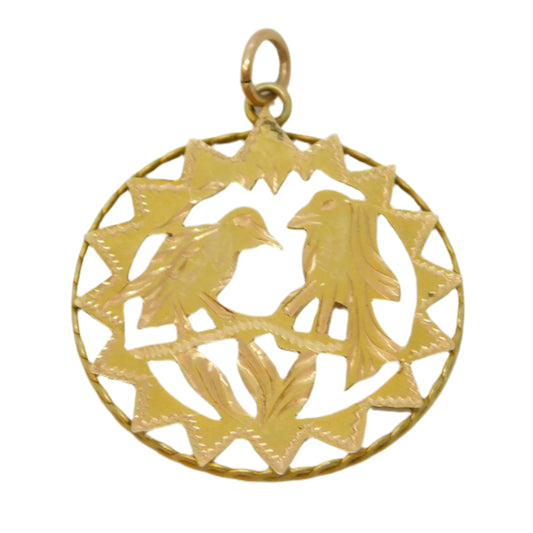 Gold pendant with intricate design on a light gray background