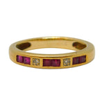 Gold ring with embedded red stones and a diamond on a light gray background