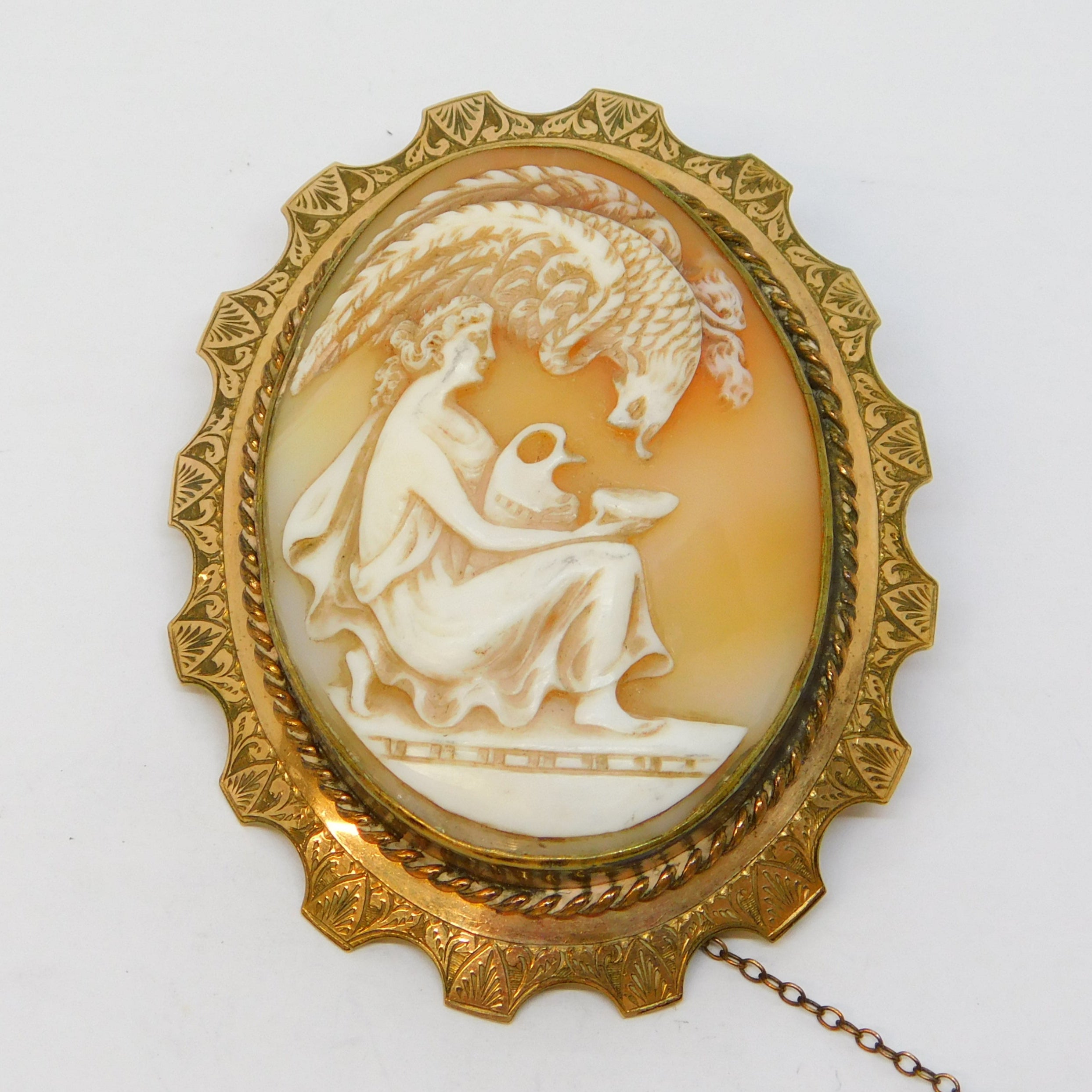 Vintage-style cameo brooch with gold frame on a white background