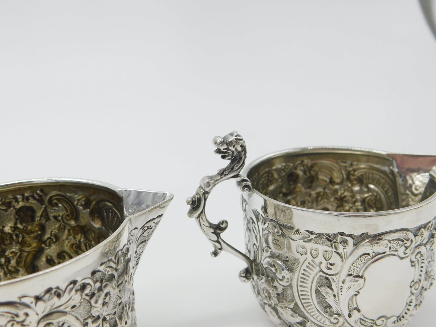 Pair Victorian Sterling Silver Cupid, Floral, Mythic Cream Jugs Antique 1900