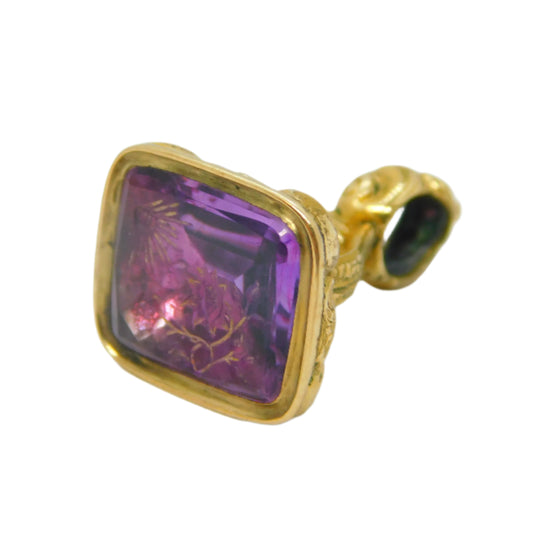 Gold pendant with a purple gemstone on a white background
