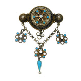 Decorative brooch with turquoise stones and floral designs on a white background