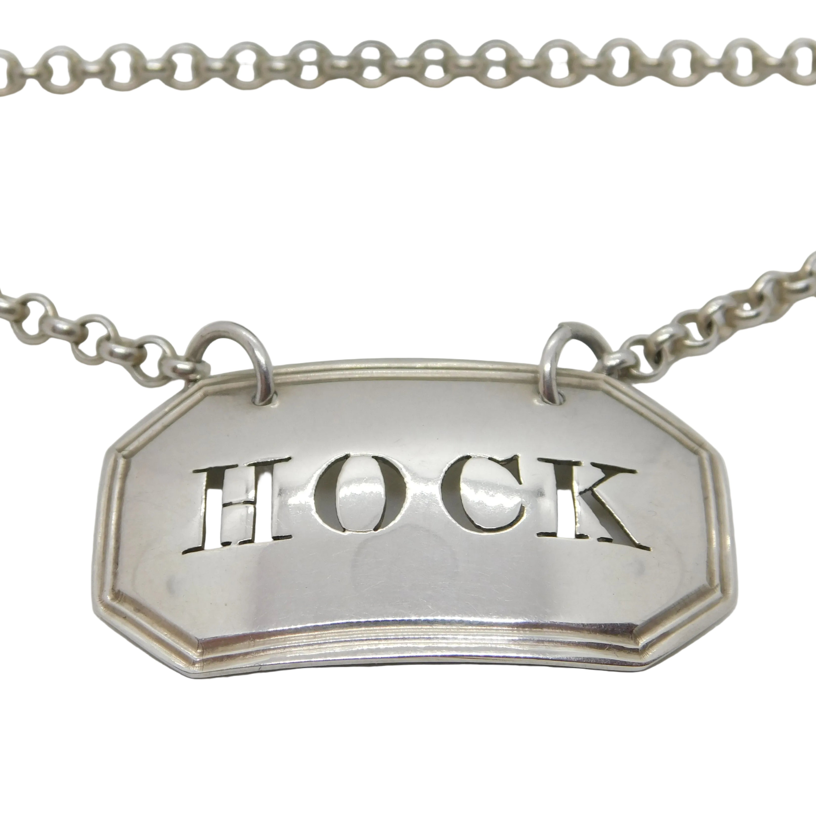 Antique sterling silver Hock wine decanter label with the word 'HOCK' embossed on it, featuring a rectangular frame and a chain for attachment.